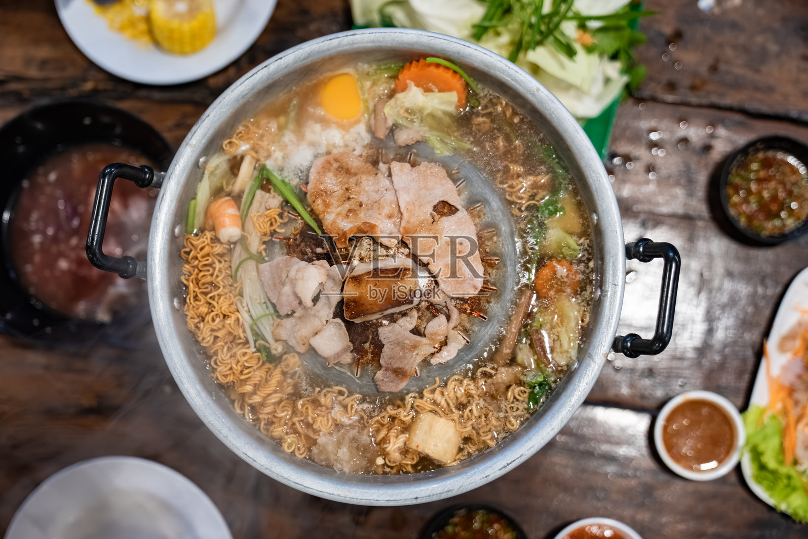 肉片和蔬菜在装满肉汤的金属烤锅中烹饪，冒着热气，中心的烤架将肉烤至金黄。照片摄影图片