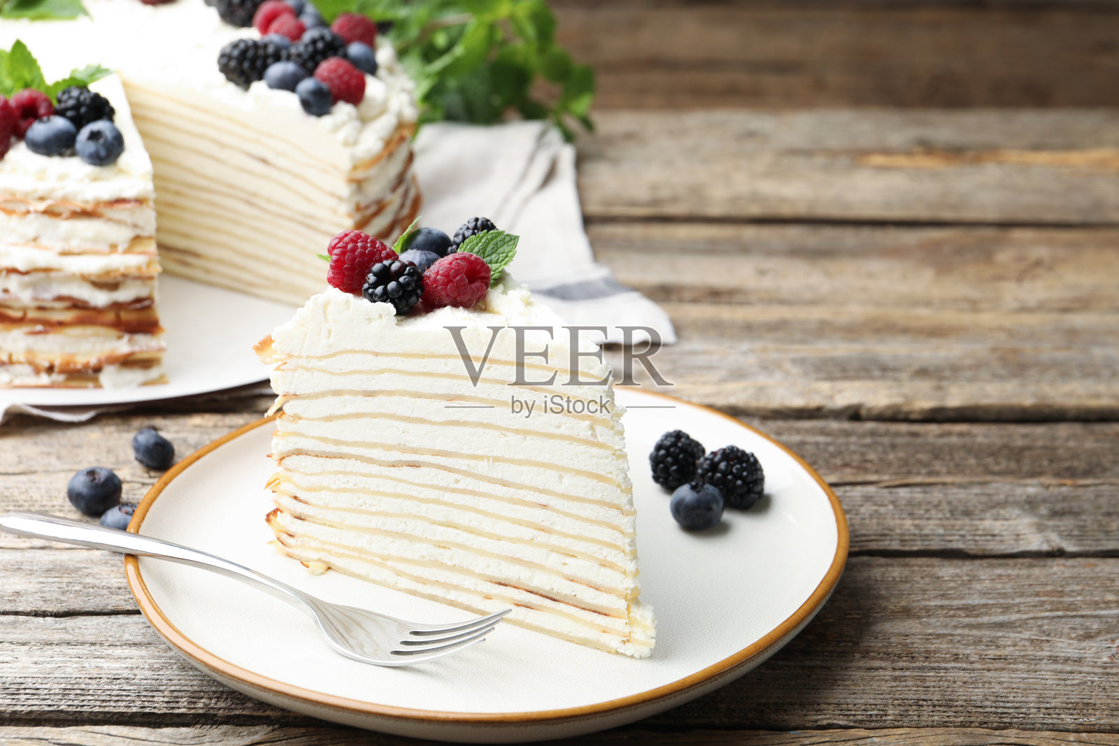 特写：木桌上摆放着一块美味的千层蛋糕，配有浆果。留有文字空间照片摄影图片