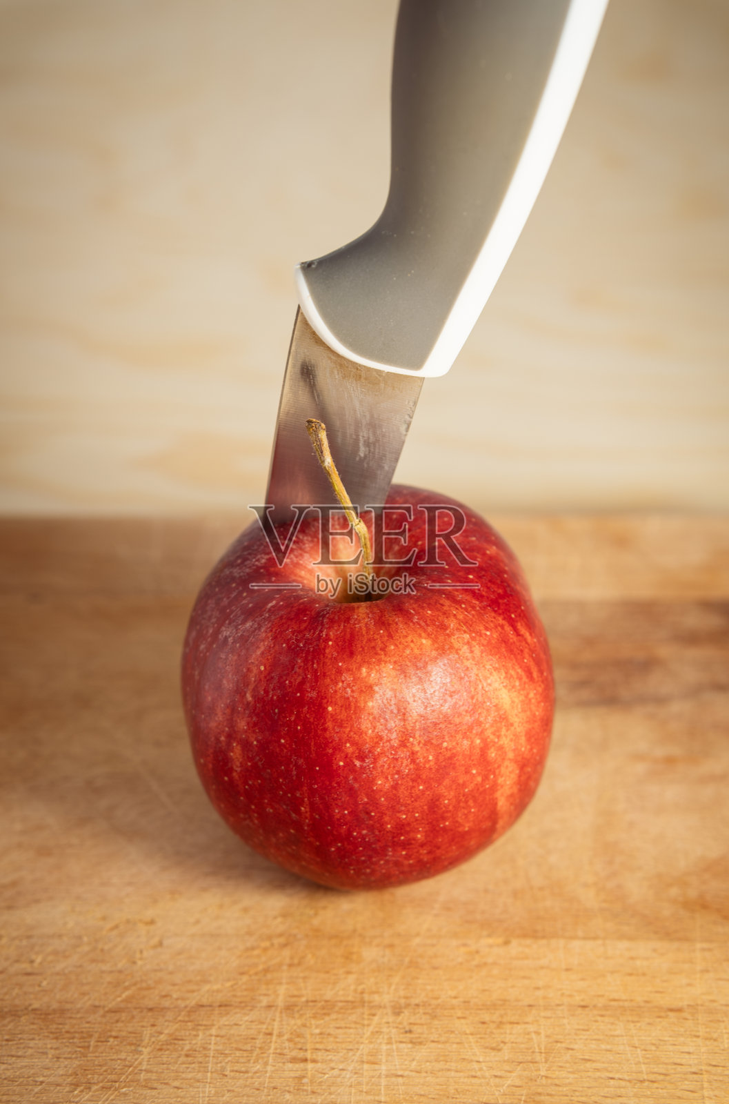 木板上，现代厨房刀锋特写插入成熟红苹果照片摄影图片