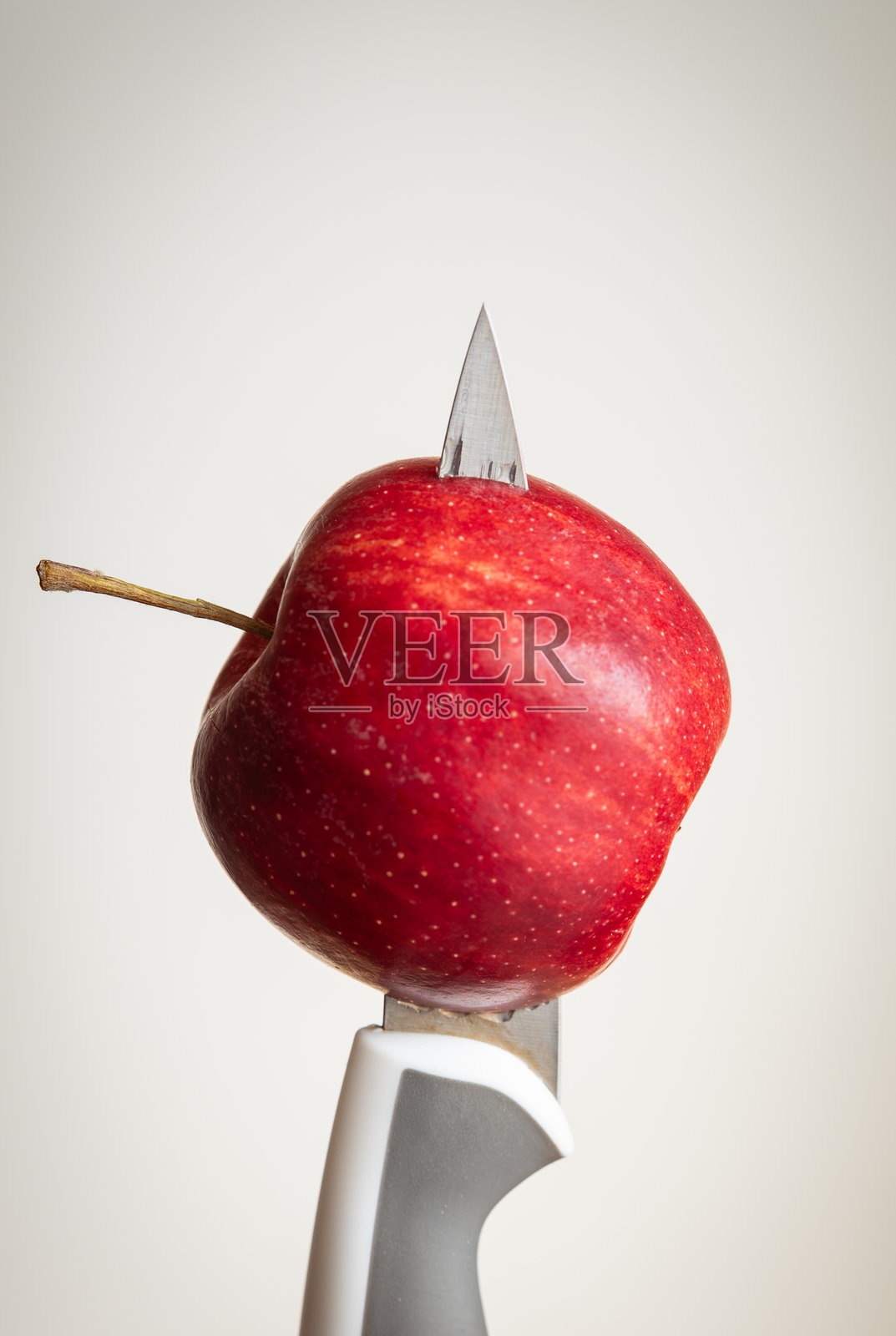 厨房刀具刺穿成熟红苹果的孤立垂直特写，背景为白色照片摄影图片