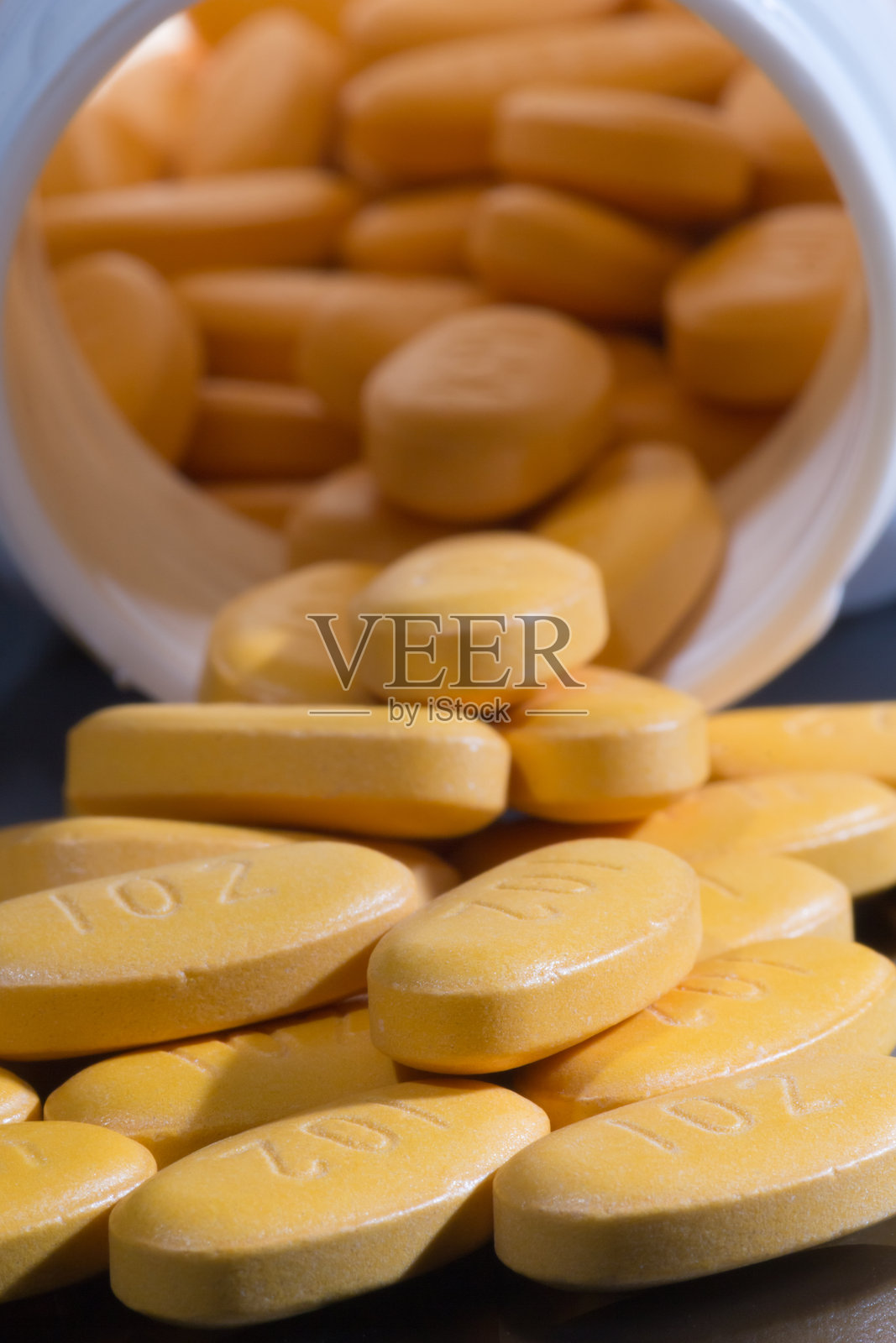 药片（或胶囊）从药瓶中倾倒而出照片摄影图片