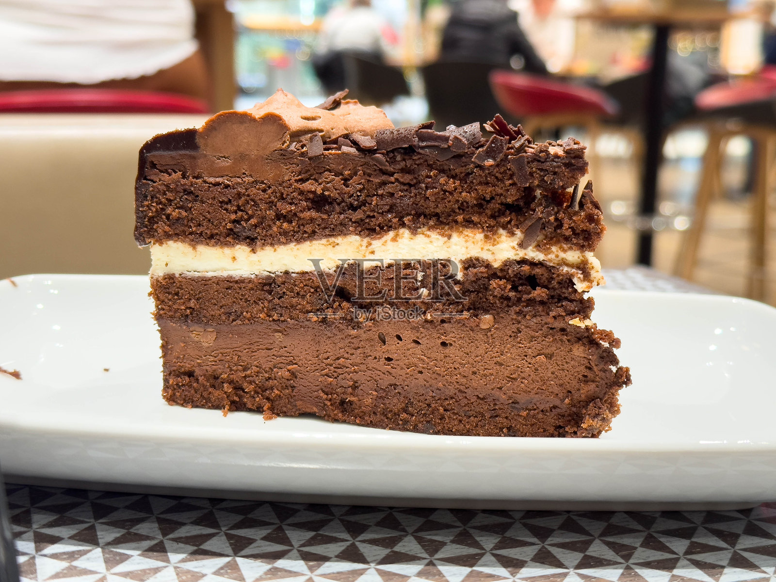 咖啡馆场景中，白色盘子里的颓废巧克力千层蛋糕切片照片摄影图片