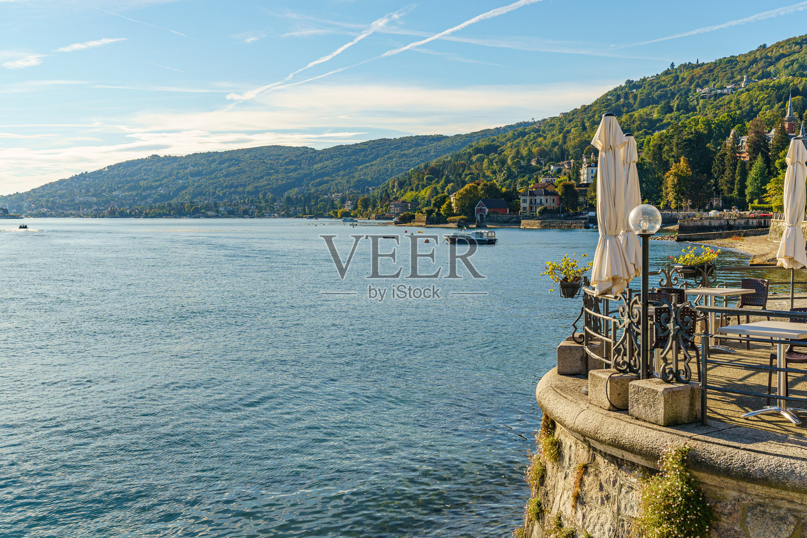 意大利巴韦诺市马焦雷湖畔的堤岸，湖水平静清澈，背景可见群山照片摄影图片