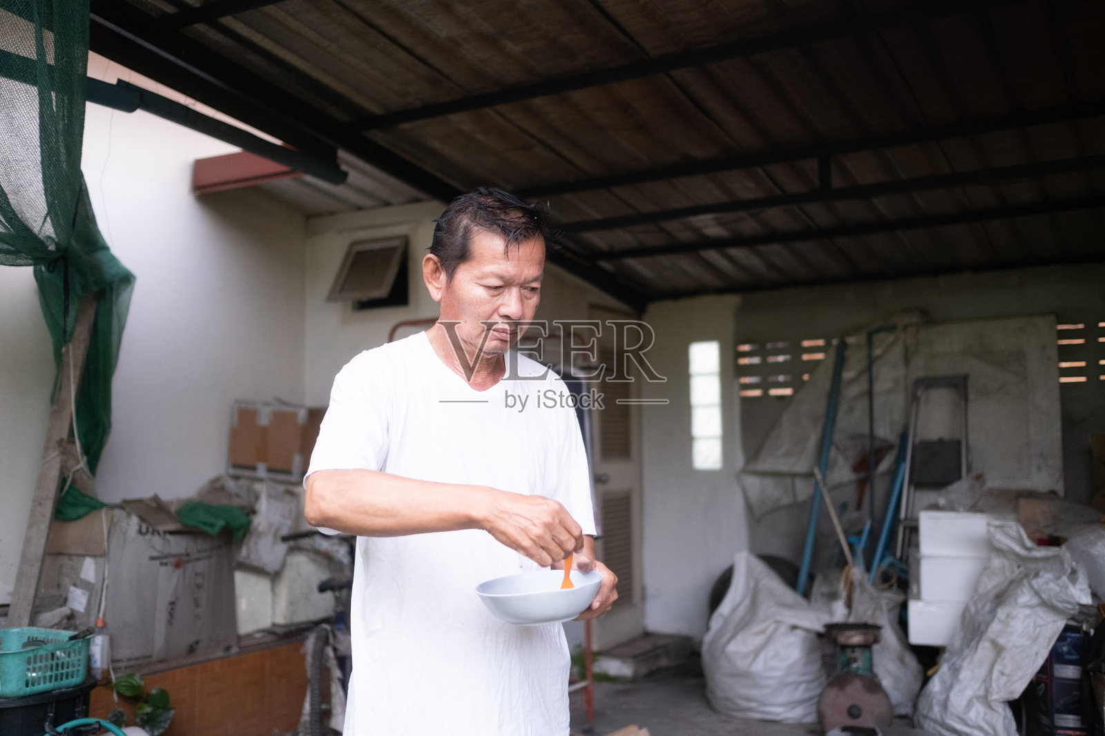 一个男人手里拿着一碗食物，站在车库里照片摄影图片