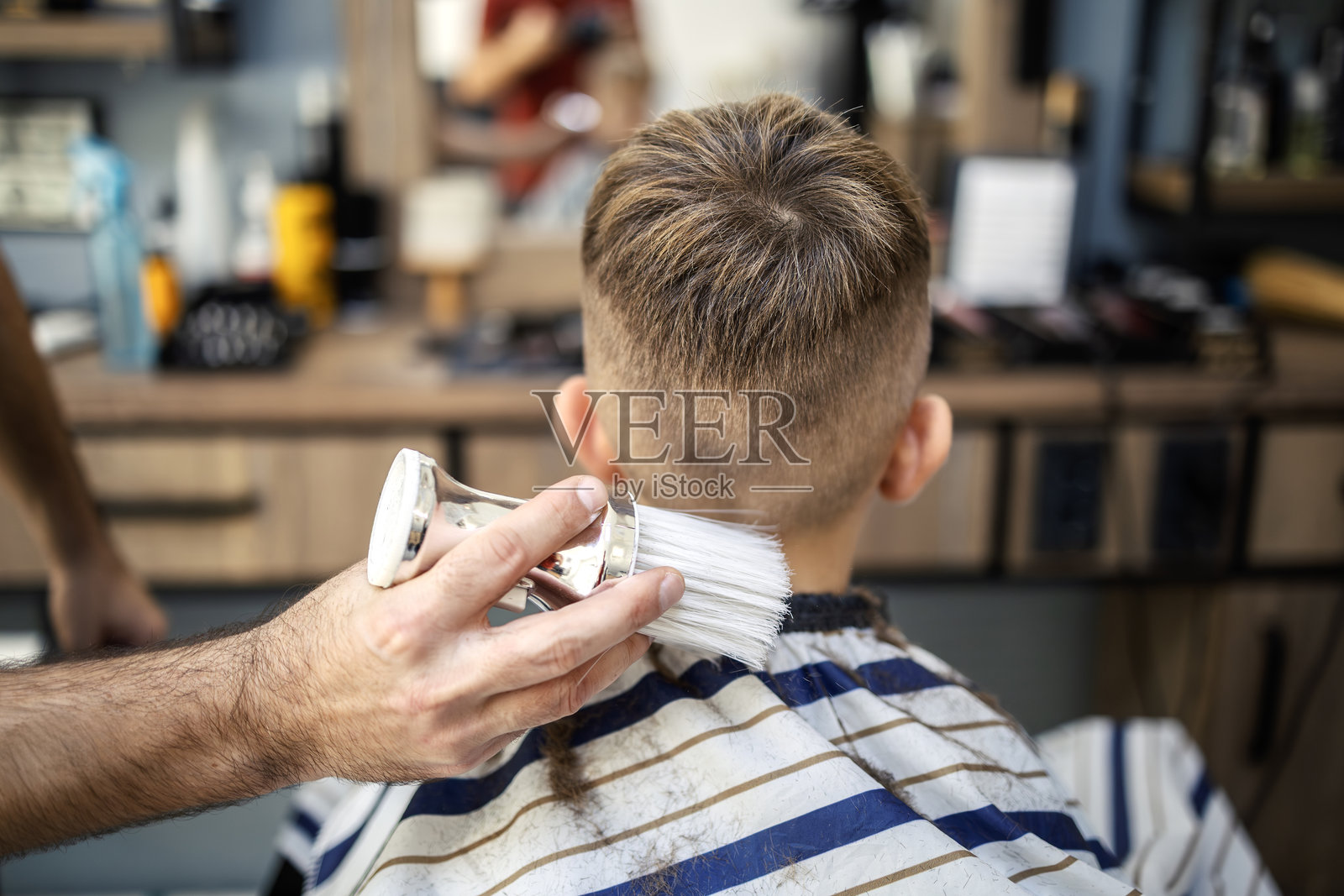 理发师在专业沙龙为男孩理发后清理脖子照片摄影图片