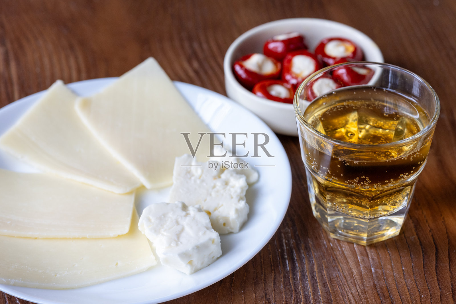 一杯威士忌，配上一盘欧洲奶酪和一小碟辣椒酿开胃菜照片摄影图片