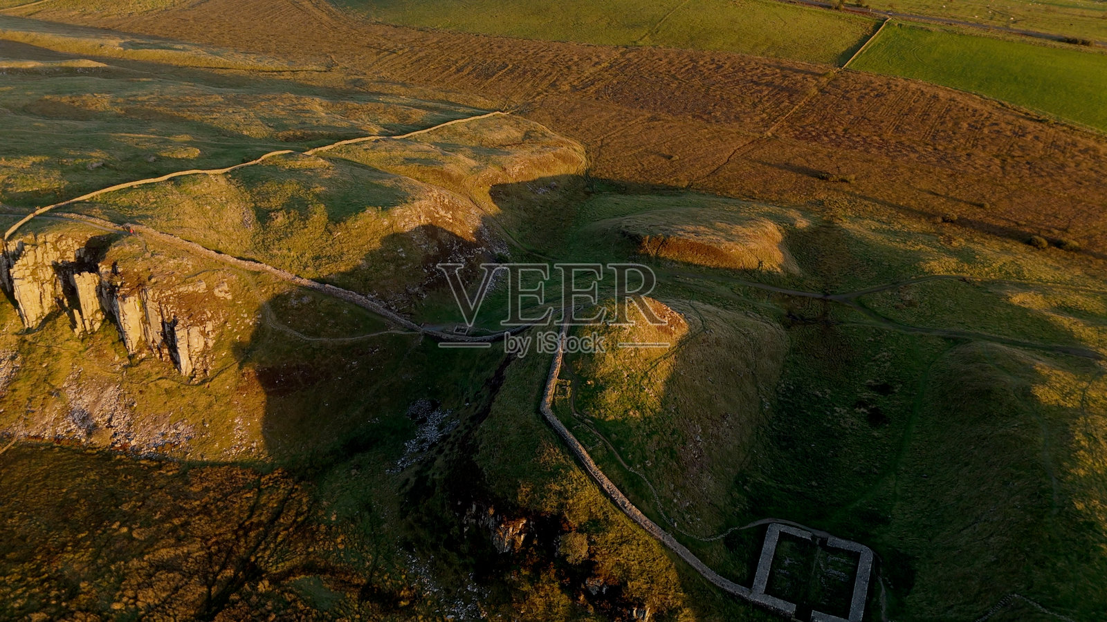 英国诺森伯兰郡的枫树谷（树木被砍伐后）在黄金时刻由无人机拍摄，位于哈德良长城旁的斯蒂尔里格。照片摄影图片