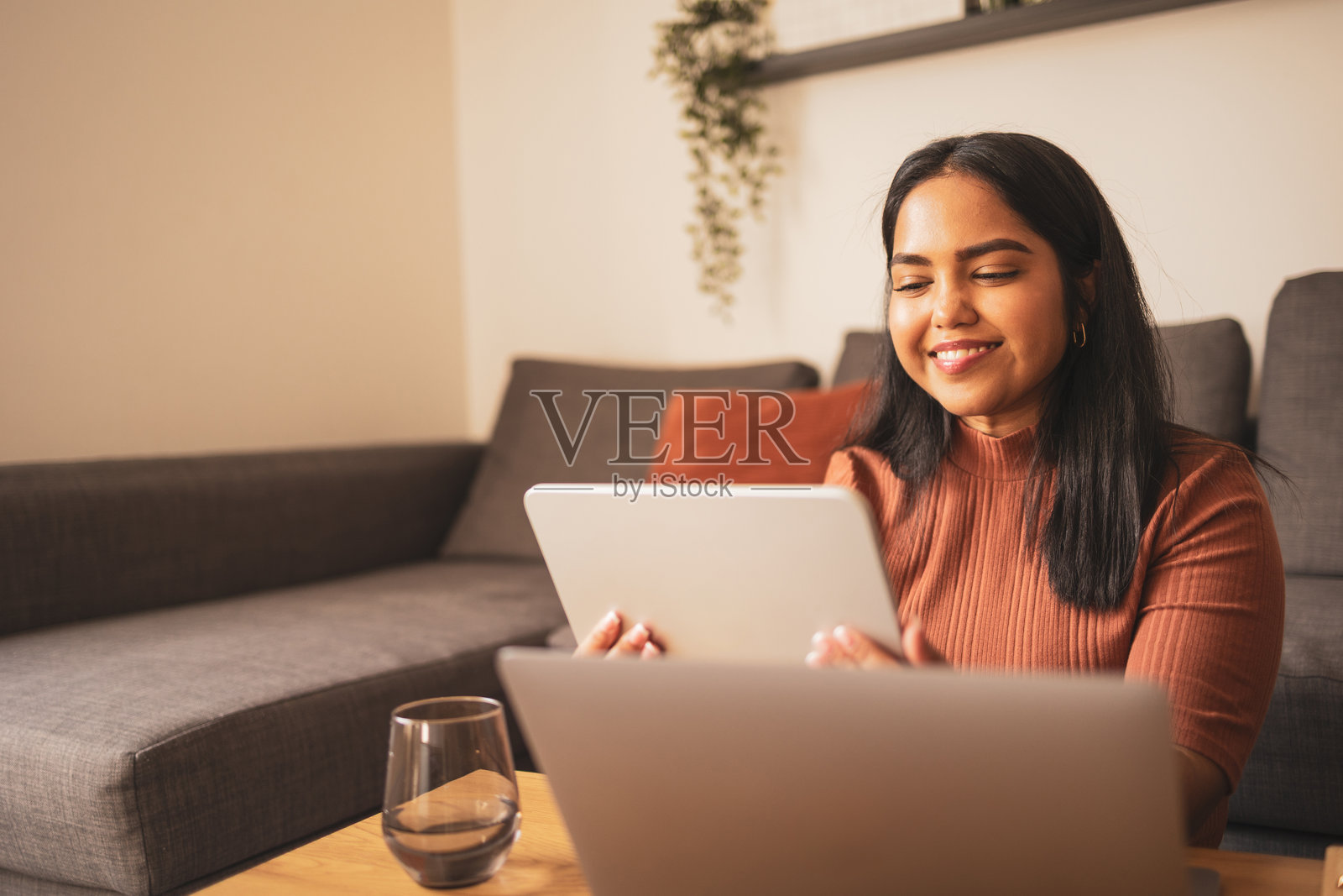 一位女士在家中使用平板电脑，脸上带着明亮的笑容照片摄影图片