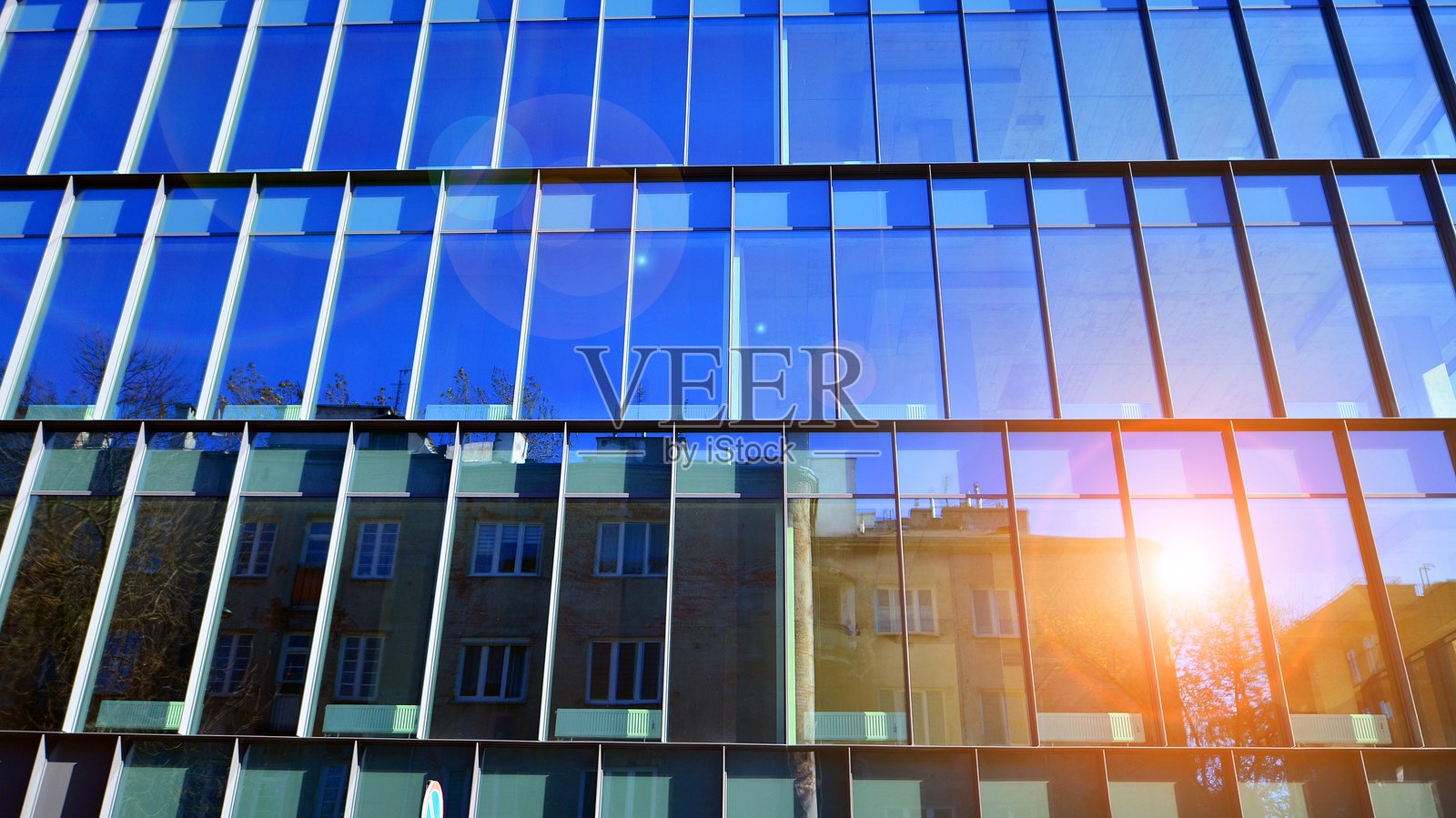 从低角度仰视，蓝天映衬下的现代建筑，拥有众多窗户。照片摄影图片