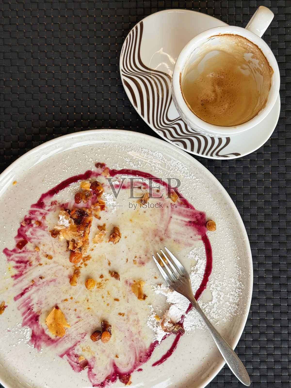 享用过的甜点盘和卡布奇诺杯，带有糕点碎屑和浆果糖浆痕迹，暗示着刚刚享用的舒适感恩节美食。体现了令人满意的秋季风味和温馨的时刻。照片摄影图片