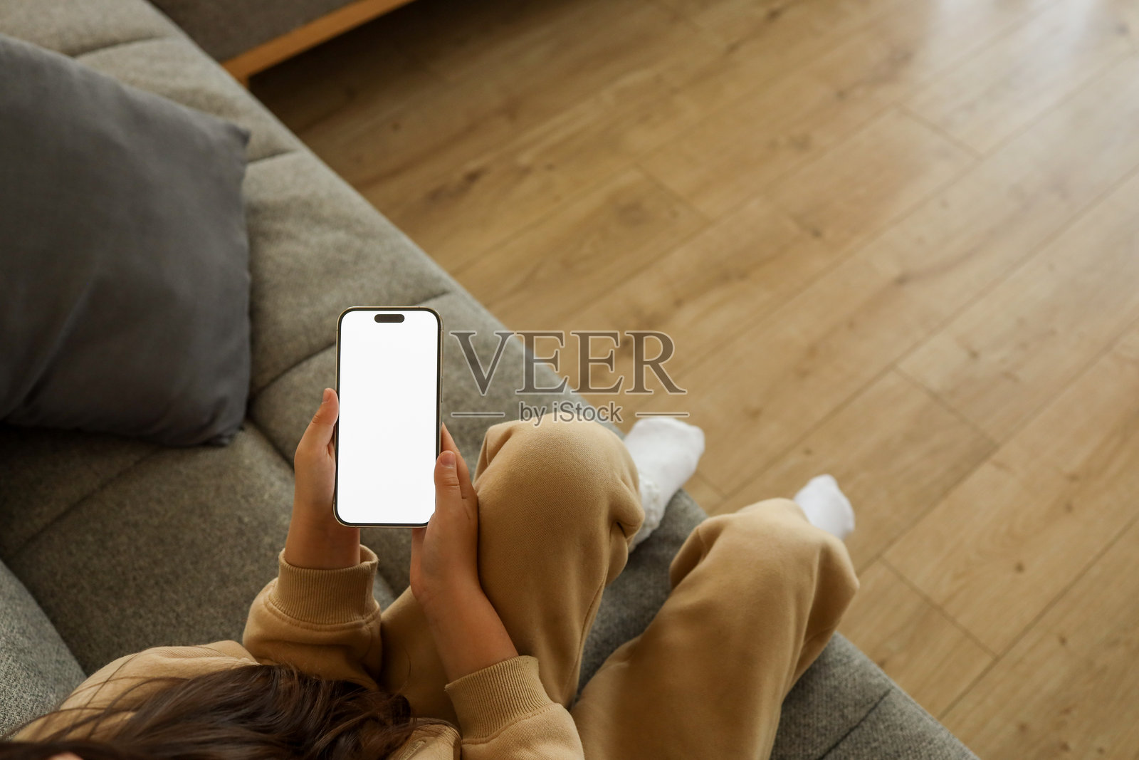一个人躺在沙发上放松，手里拿着一部屏幕空白的智能手机照片摄影图片
