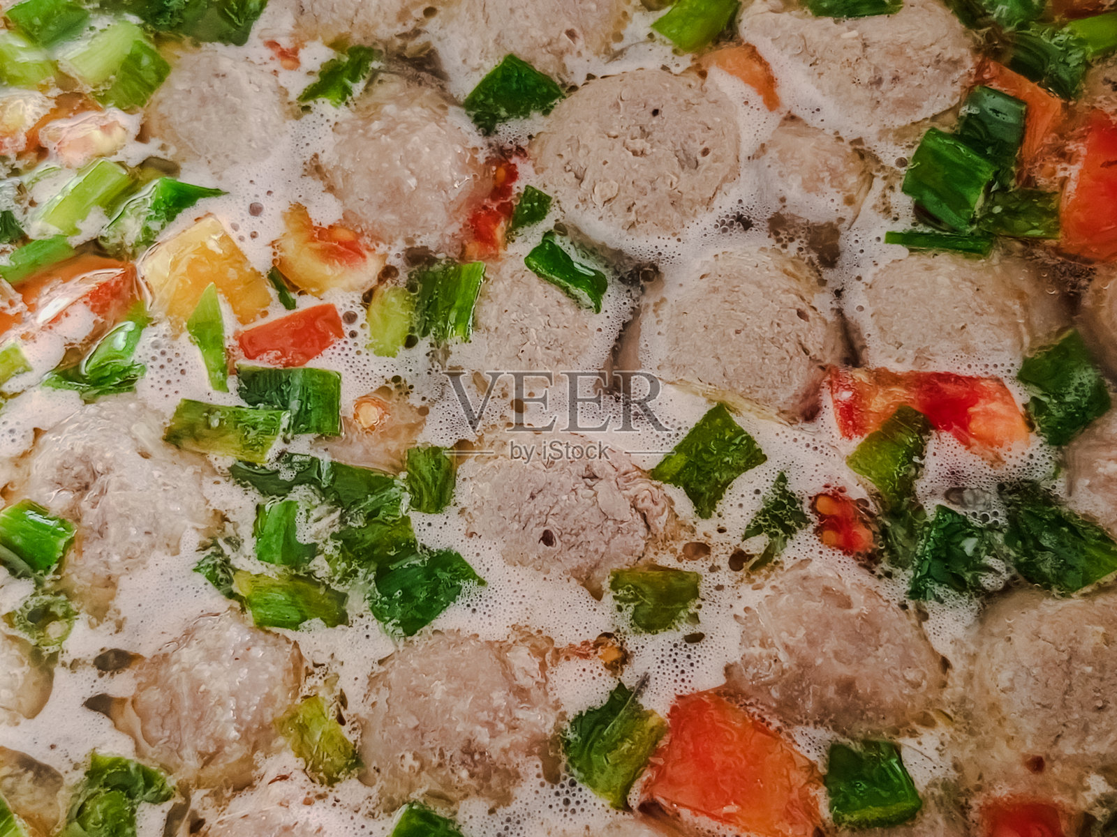 印尼巴索肉丸汤特写，汤中煮着肉丸，撒有葱花和番茄，俯视角度照片摄影图片