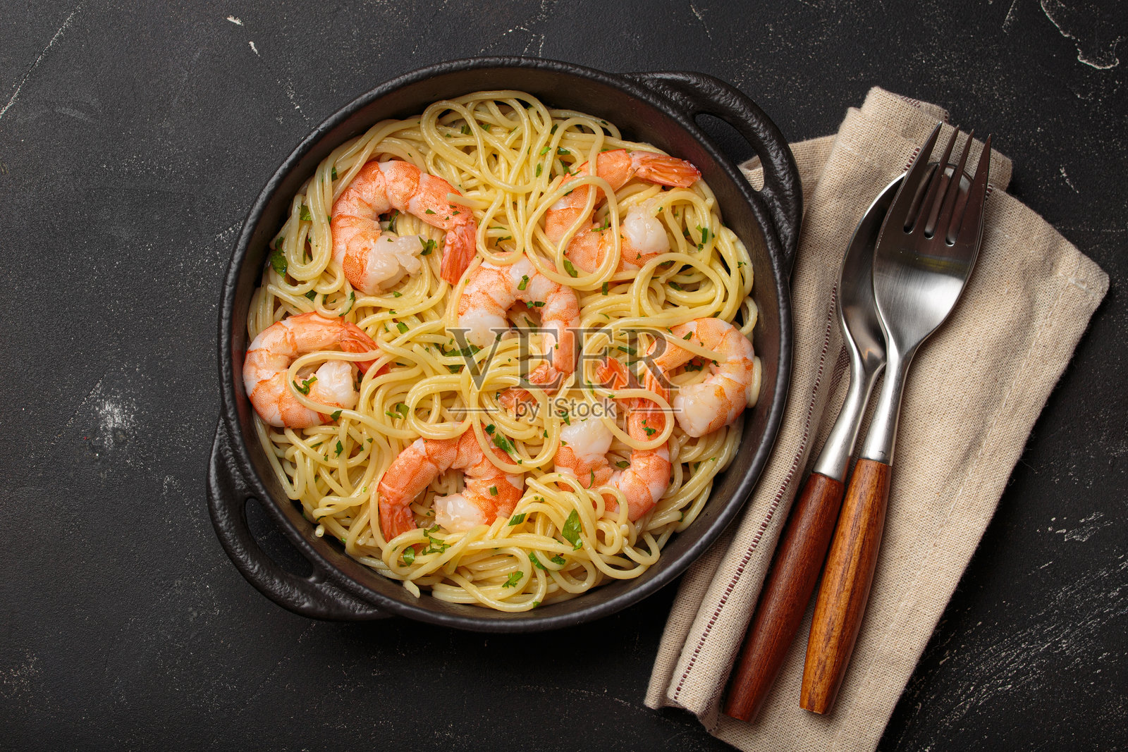 黑色背景上的美味海鲜意面，配有虾、柠檬和欧芹，俯视角度照片摄影图片