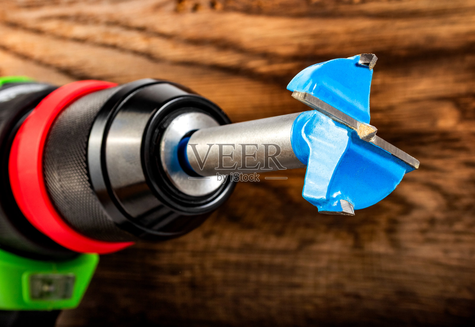 木质背景上的无绳电钻，配有快速释放夹头和钻头。照片摄影图片