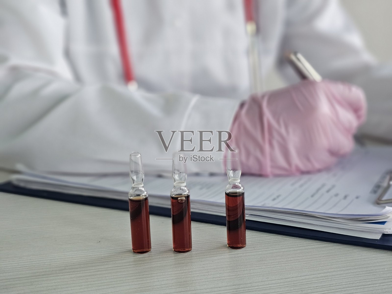 医生正在检查装有红色液体疫苗或维生素B的试管。盐酸硫胺素溶液概念照片摄影图片