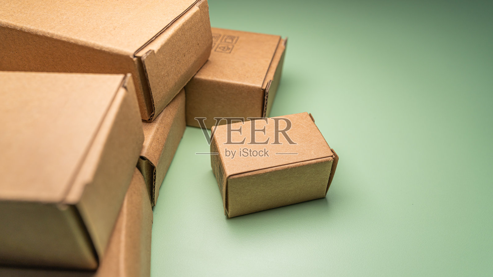 绿色背景下，特写镜头展示着代表现代在线零售的空白棕色纸板包裹。照片摄影图片