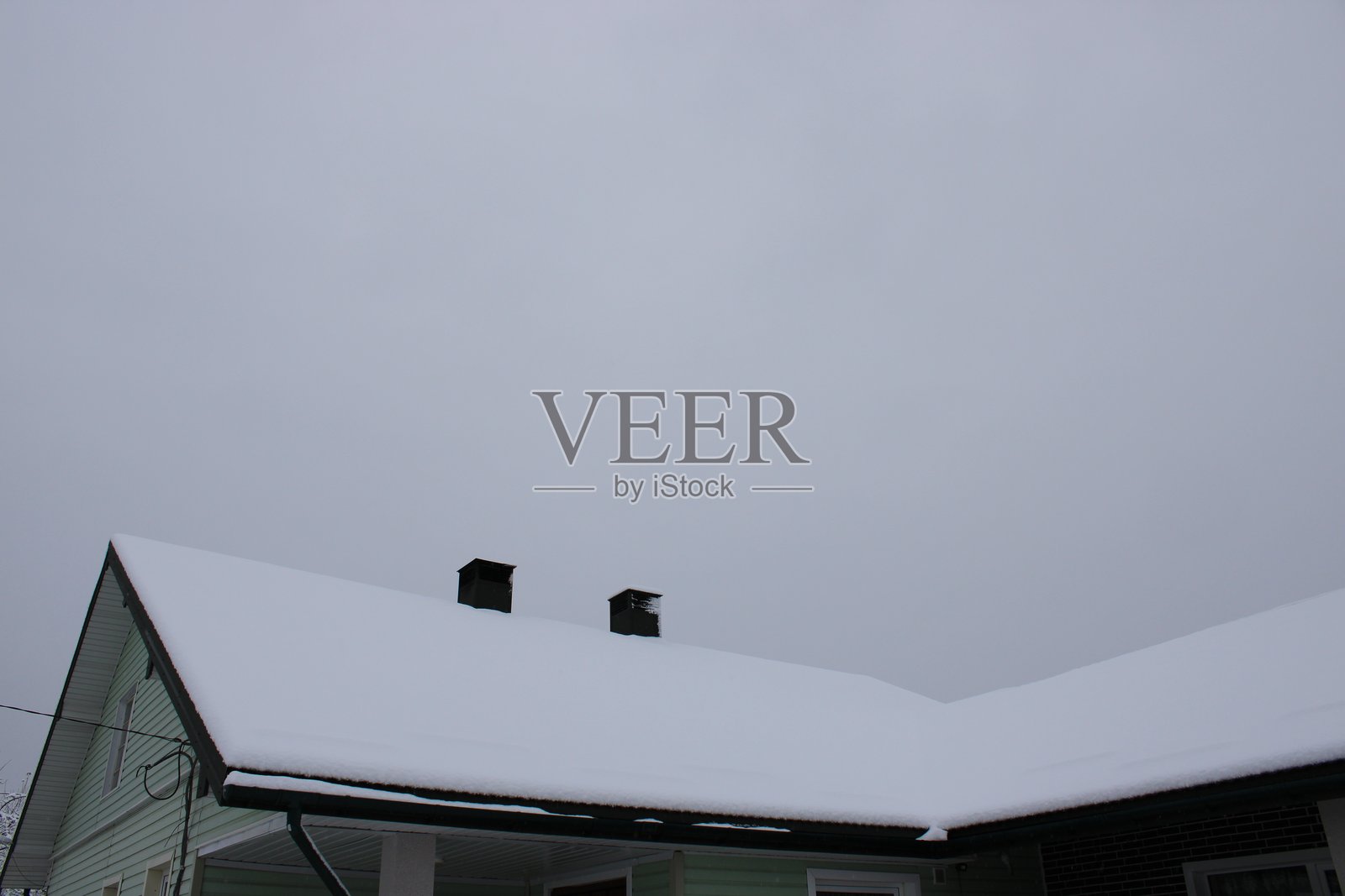 冬天，阴天，雪覆盖着房子的屋顶照片摄影图片