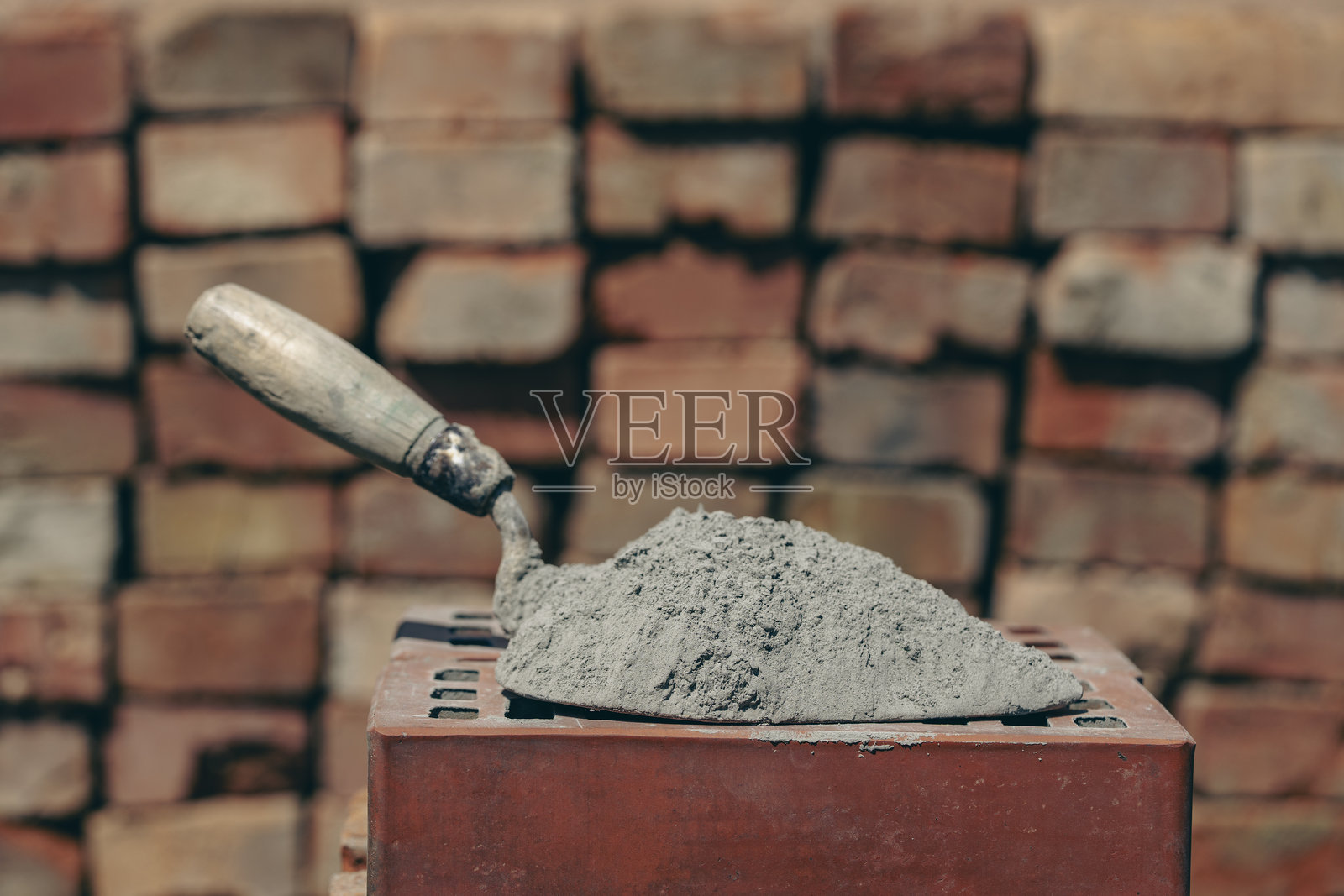 干燥的水泥或砂浆。建筑工地上红色砖块上的水泥粉末和抹刀，特写照片摄影图片