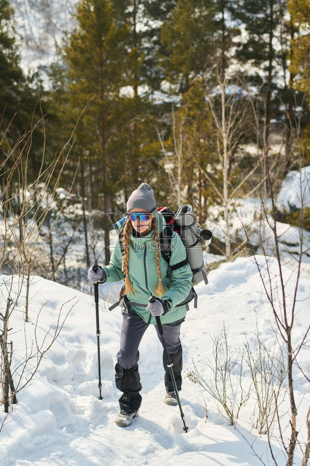 冬季，年轻女子在雪林中徒步上山照片摄影图片
