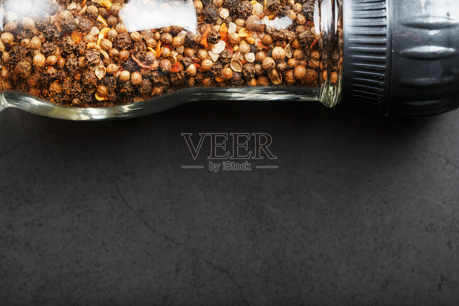 黑色背景下，玻璃研磨罐中盛放着混合的调味料、香料和香草。照片摄影图片