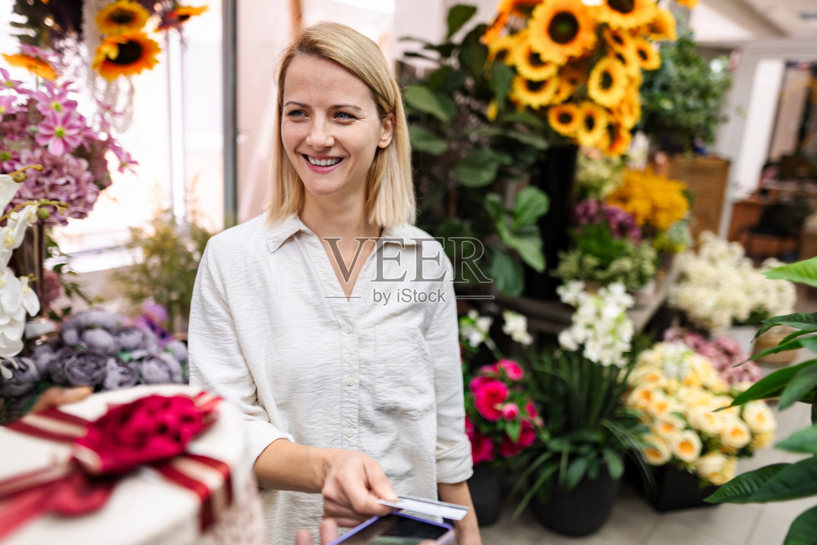 微笑的花店店员在花店里接受顾客的信用卡付款照片摄影图片