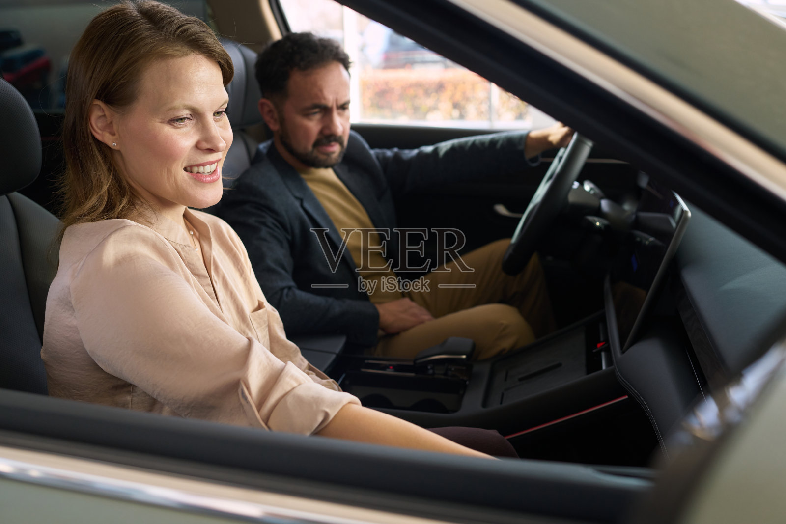 年轻女子在汽车经销商处与中年男子一同坐在车内照片摄影图片