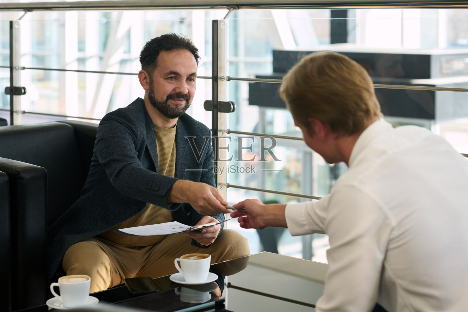 年轻男子在汽车经销商处递名片给中年男子照片摄影图片