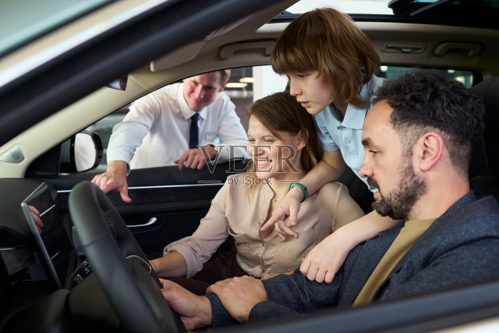 一家人正在咨询汽车销售人员，同时在查看车内饰照片摄影图片