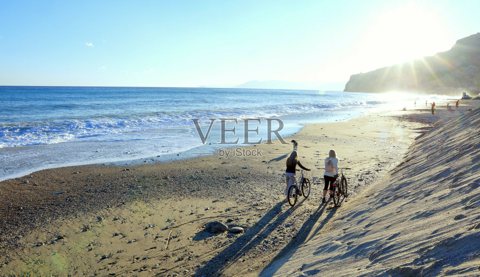 日落时分，成熟的女性在海滩上骑自行车照片摄影图片