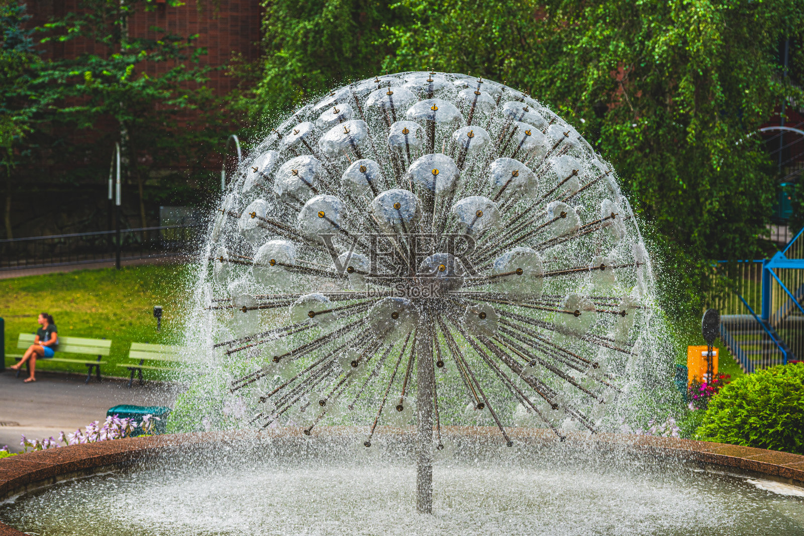户外的喷泉以圆形图案喷洒水柱。照片摄影图片