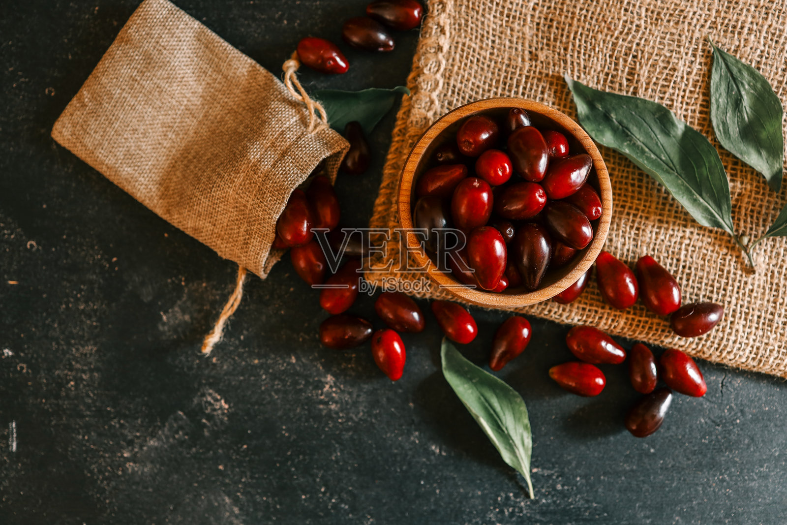 新鲜的覆盆子从粗麻袋和木碗中倾泻而出照片摄影图片