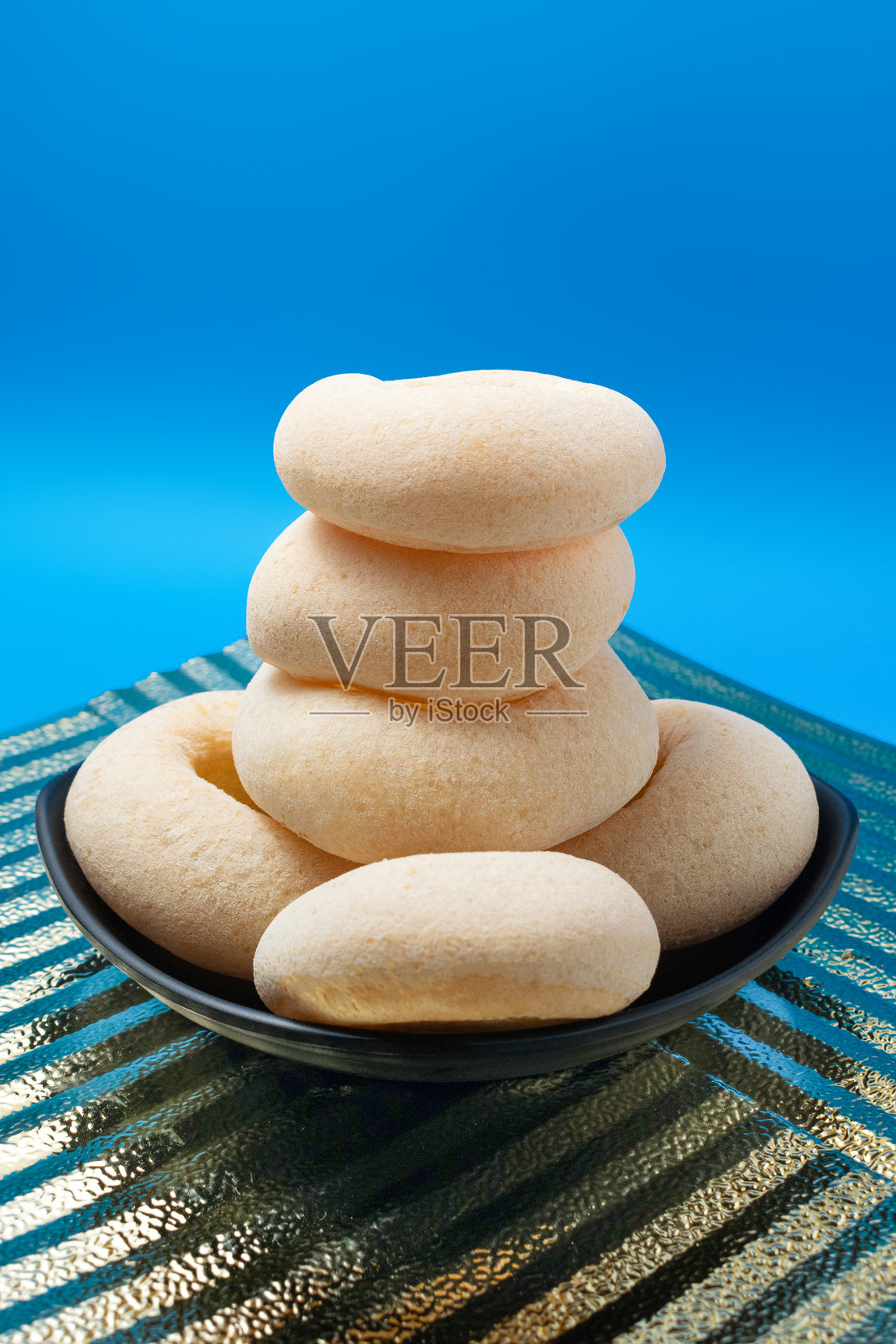 黑色盘子里的木薯卷堆叠在深蓝色和金色背景前。照片摄影图片