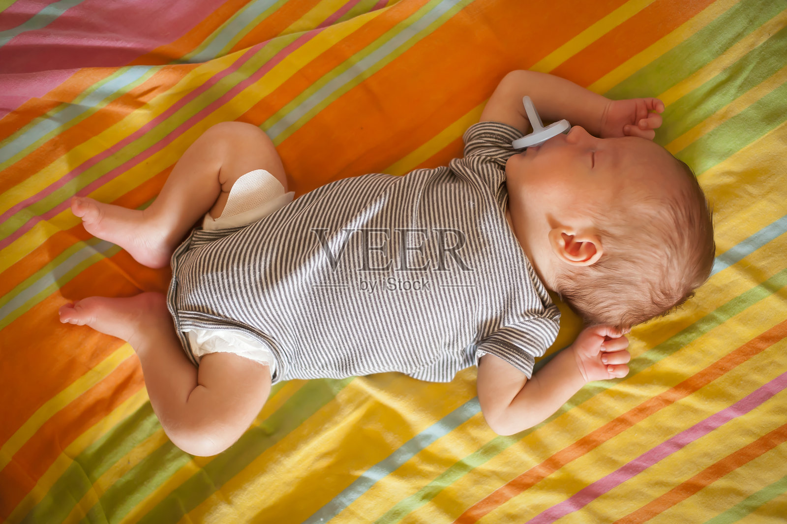 婴儿在舒适的房间里，白天安详地睡在色彩缤纷的床单上照片摄影图片