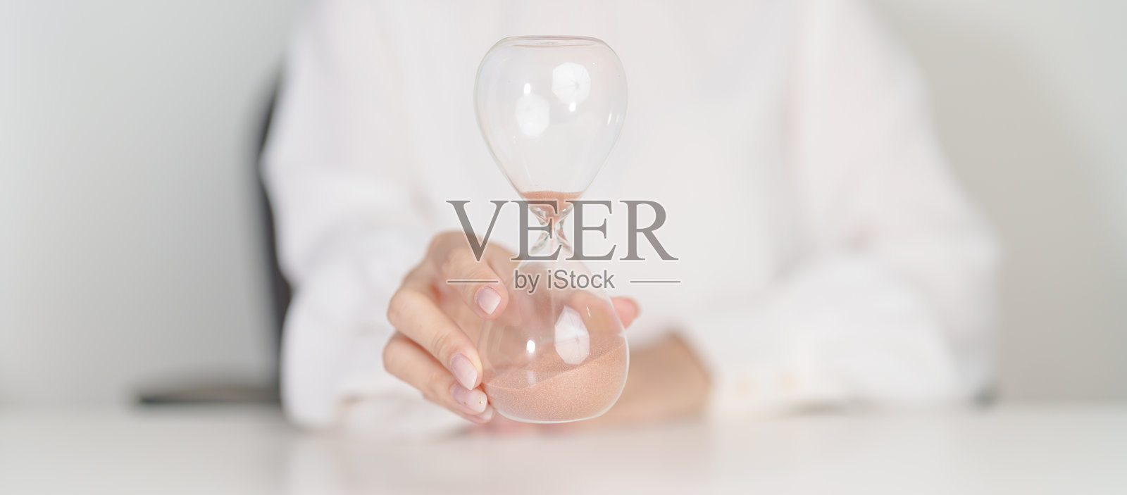 办公桌上的女子与沙漏，沙子在沙漏中流淌，象征着时间的流逝。倒计时、截止日期、人生和退休概念。照片摄影图片