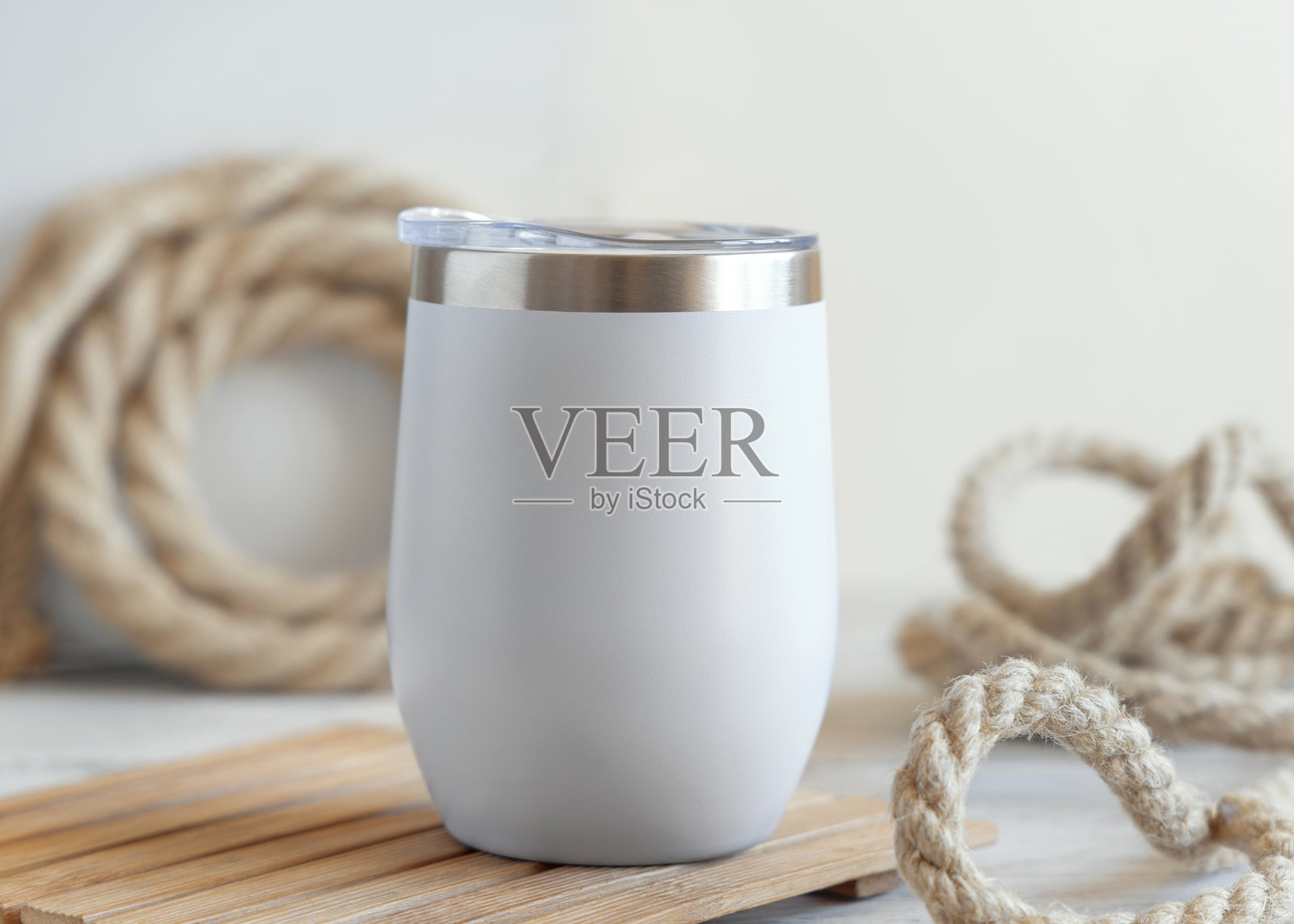白色空白不锈钢保温杯置于木头背景上，周围是粗糙的黄麻绳，特写镜头，航海风格样机照片摄影图片