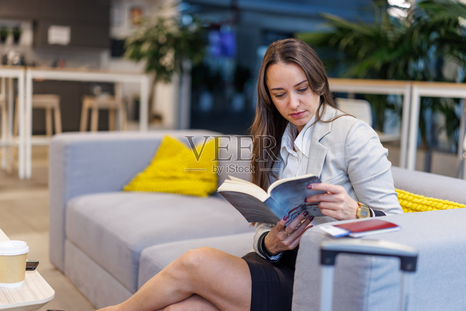 一位女士在机场休息室等待时阅读书籍照片摄影图片