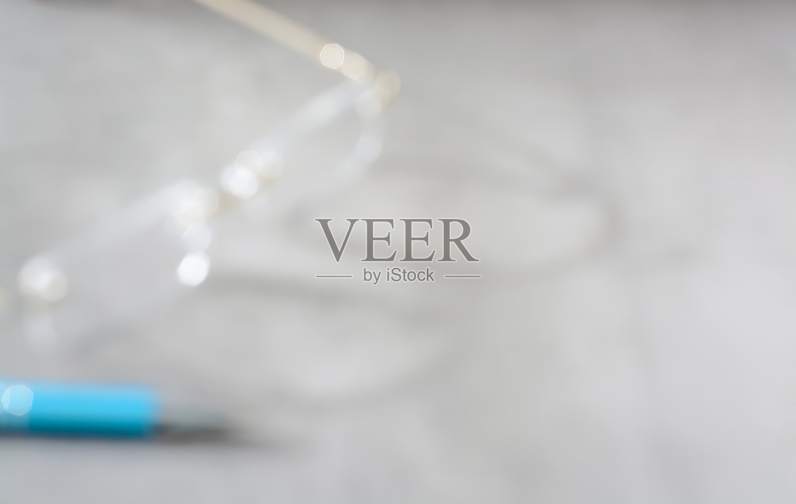 模糊的灰色背景，上面放着一副眼镜和一支钢笔照片摄影图片