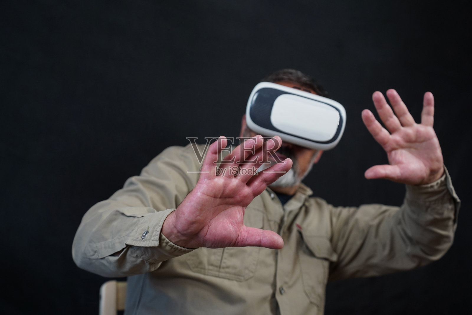 一位老年男子戴着VR眼镜，背景为黑色照片摄影图片