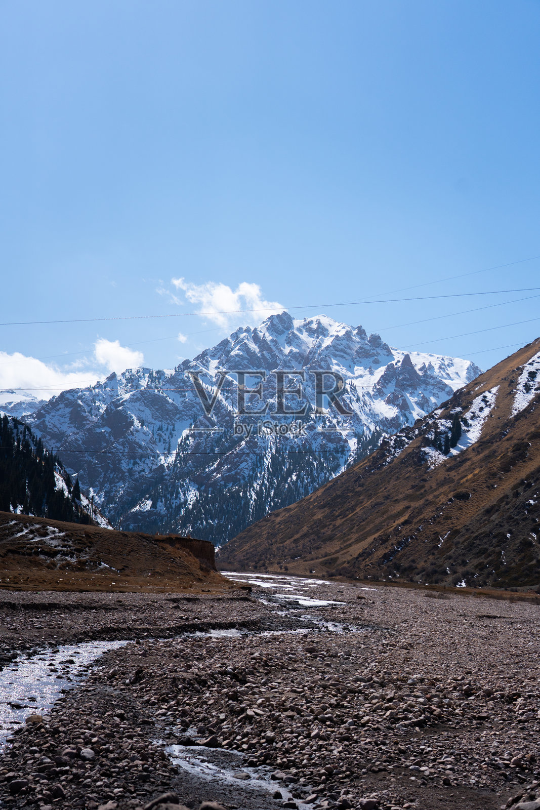 崎岖的河床通往山谷，远处是雄伟的雪山。照片摄影图片