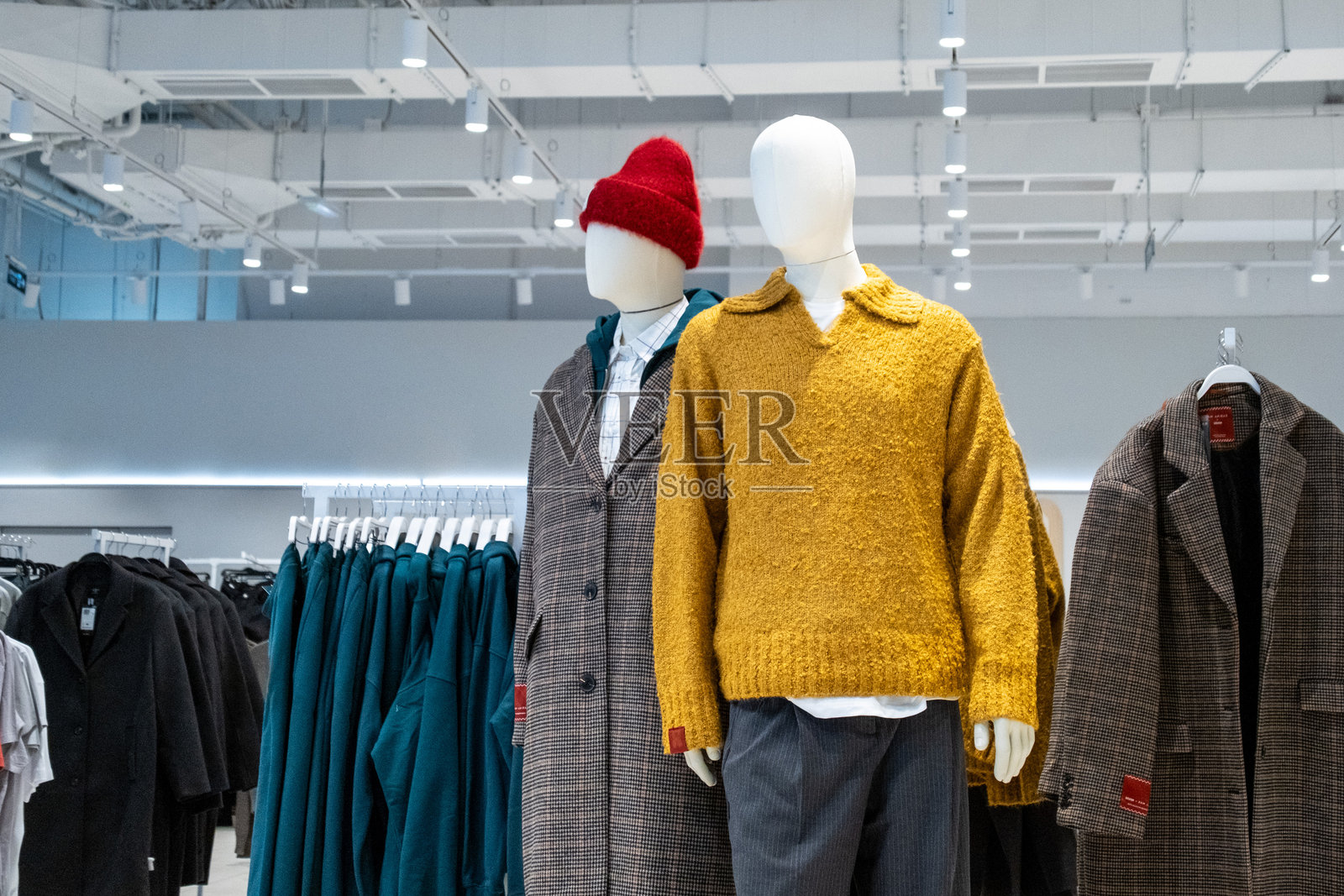 商店里展示着穿着时尚冬装的模特，为黑色星期五的购物者展示潮流服饰。大衣、毛衣和其他服装都突出展示给潜在买家。照片摄影图片