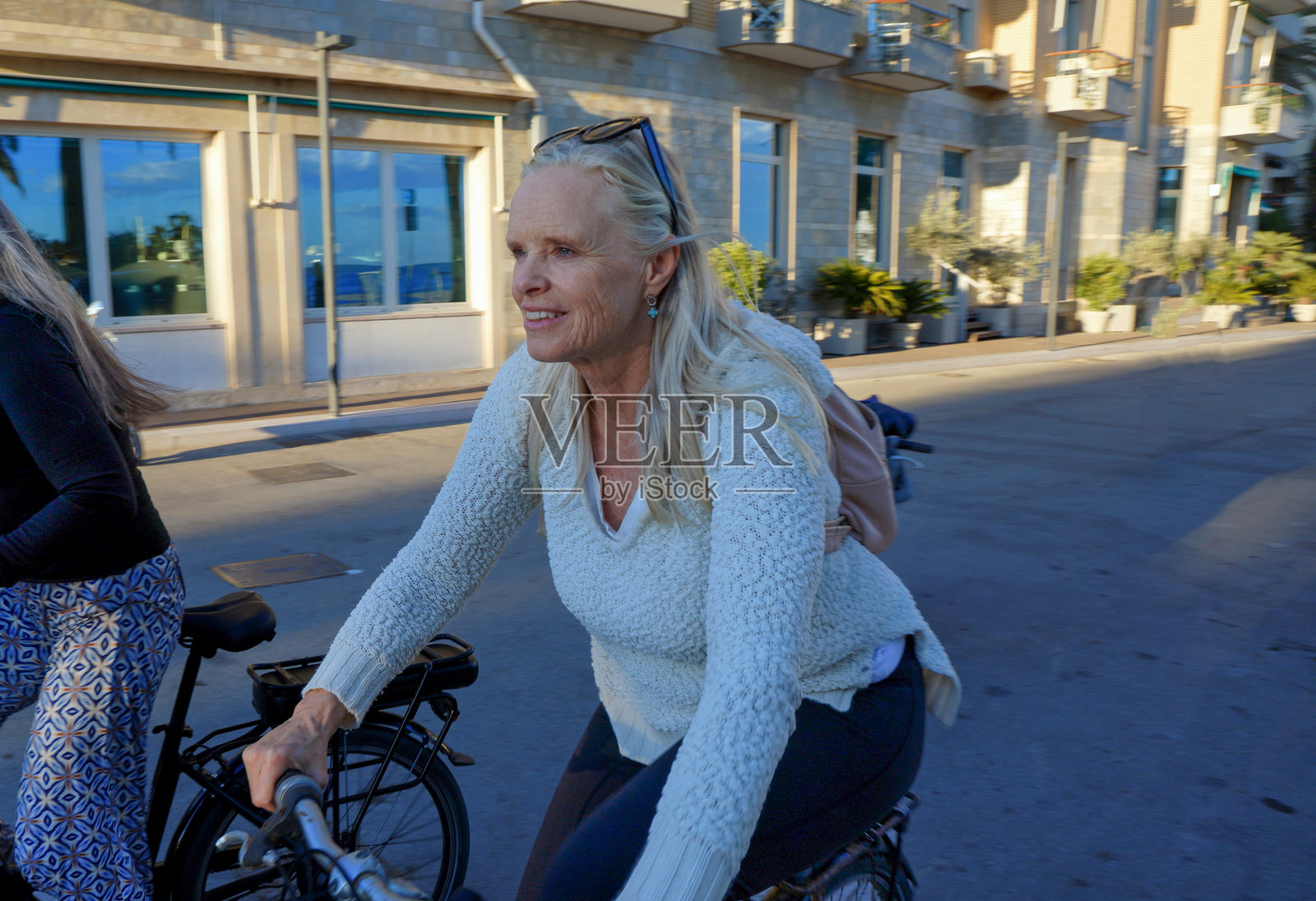 日落时分，成熟的女性在海滨大道上骑自行车照片摄影图片