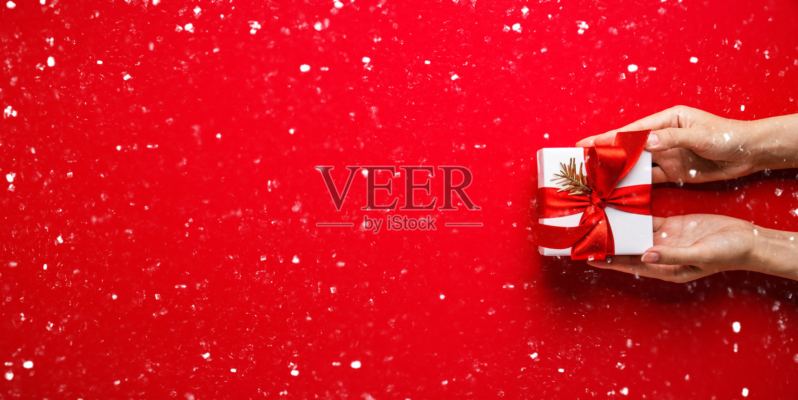 圣诞快乐，节日快乐贺卡、边框、横幅。新年。圣诞。俯视雪地红背景上双手持礼盒。冬季圣诞节日主题。俯视照片摄影图片