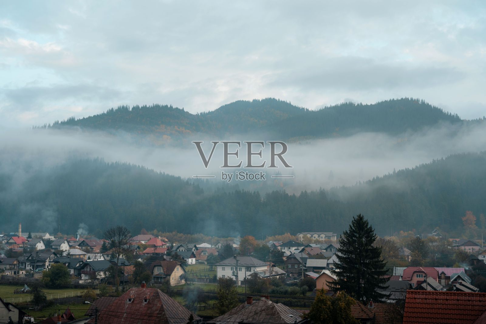 云雾缭绕的山村，屋顶色彩斑斓。照片摄影图片