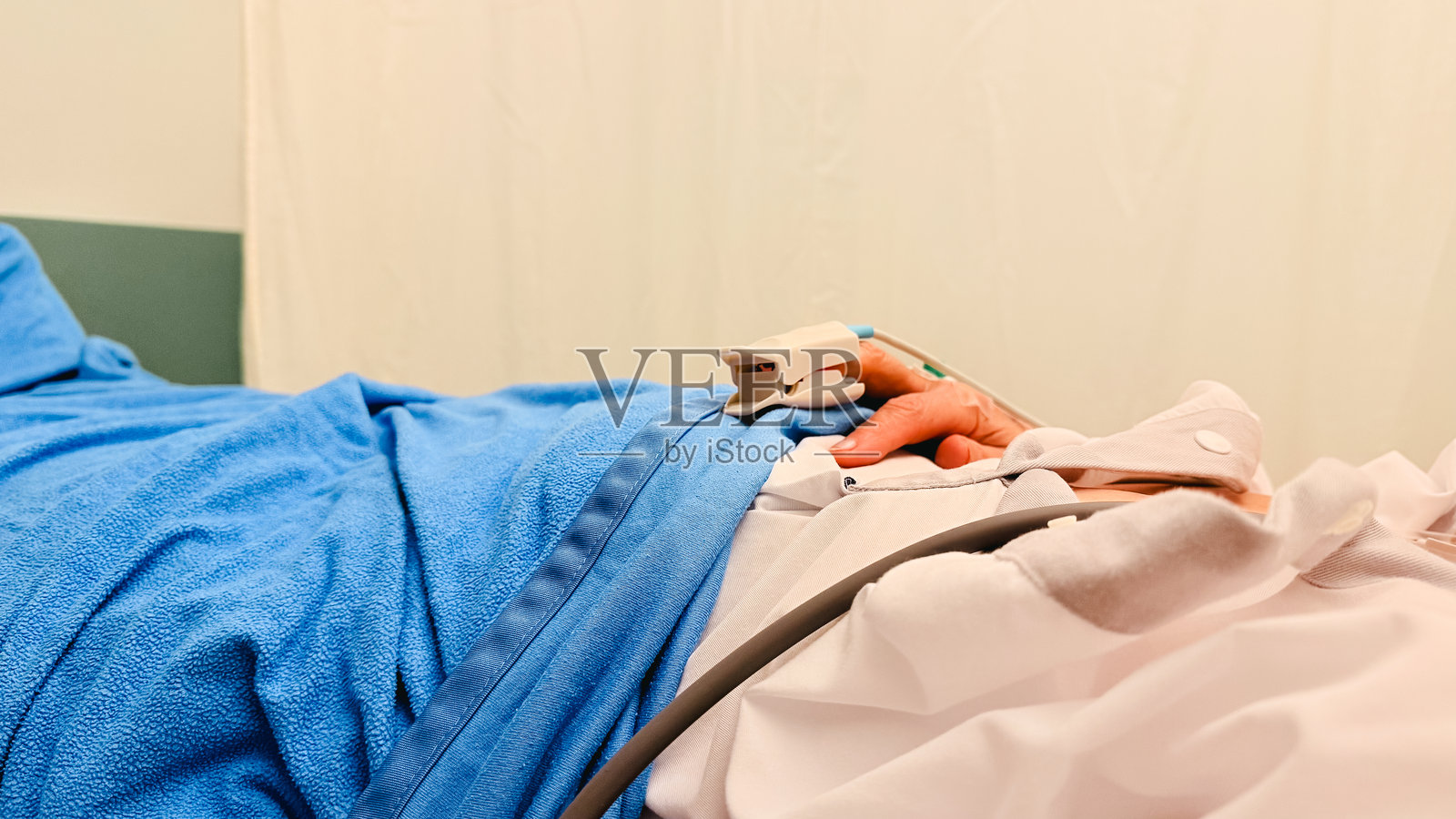 患者在临床检查和医疗治疗过程中，手连接着医疗监测设备，在医院病床上休息。照片摄影图片