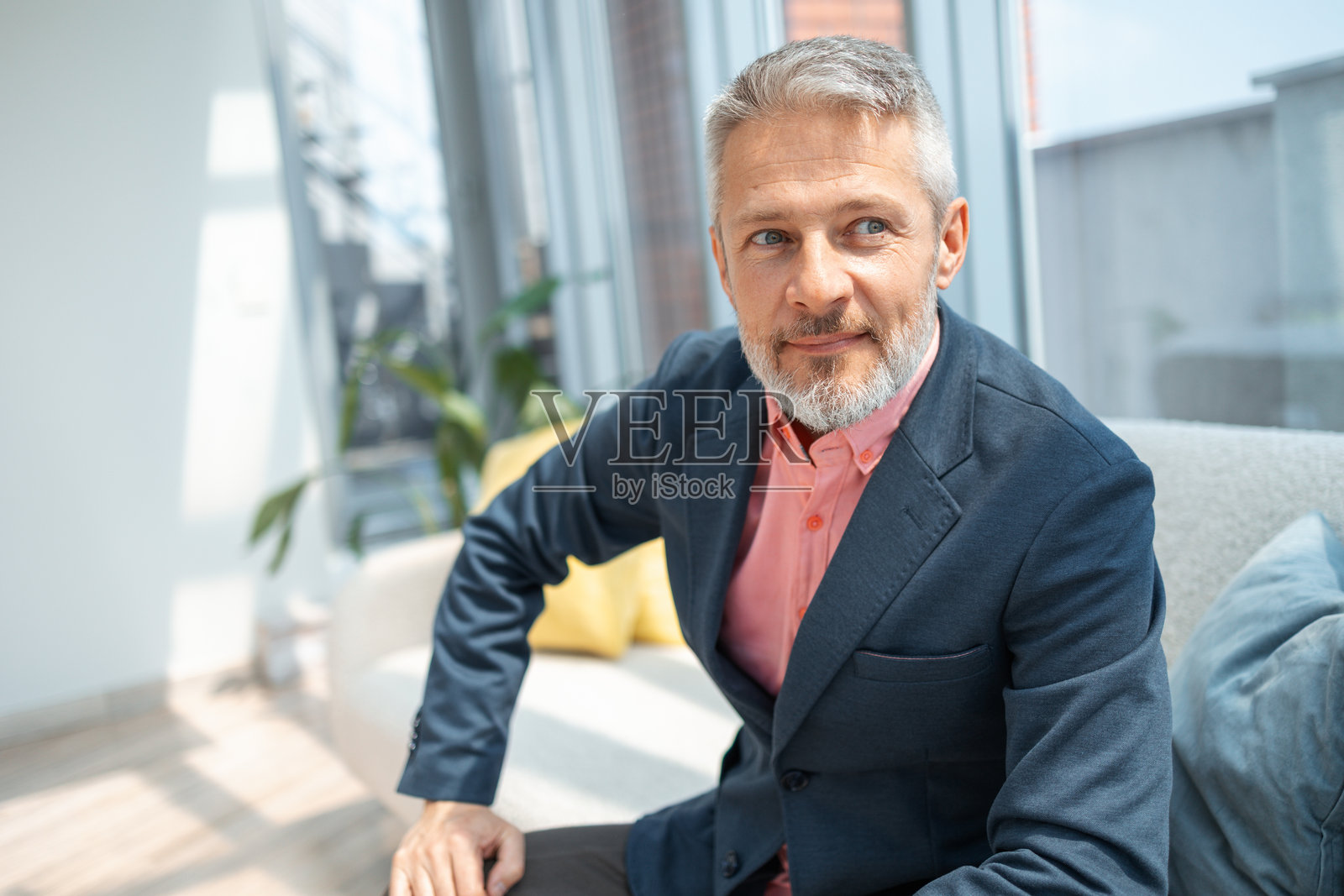 一位自信的年长男性坐在一间现代明亮的室内办公室里照片摄影图片