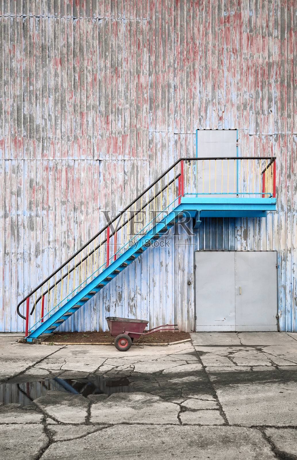 老旧工业建筑的墙壁，带有楼梯和独轮手推车照片摄影图片