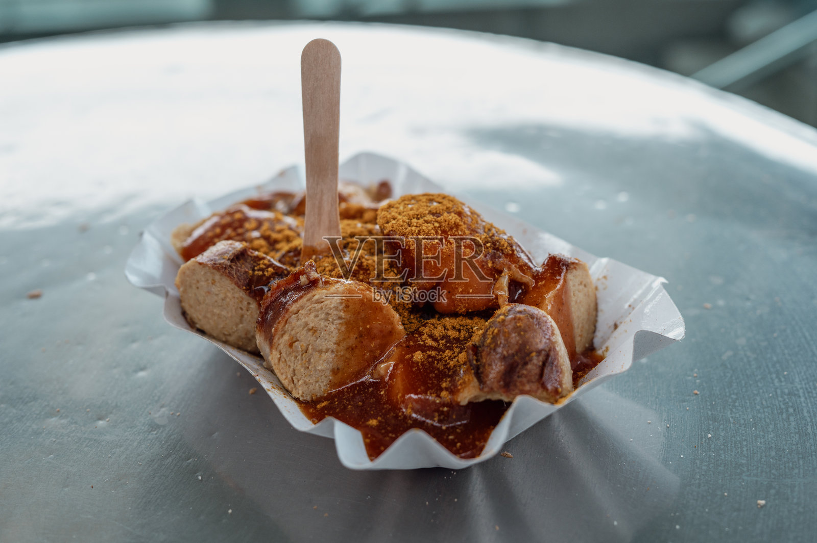 美味的咖喱香肠放在纸托盘里，配有木签照片摄影图片