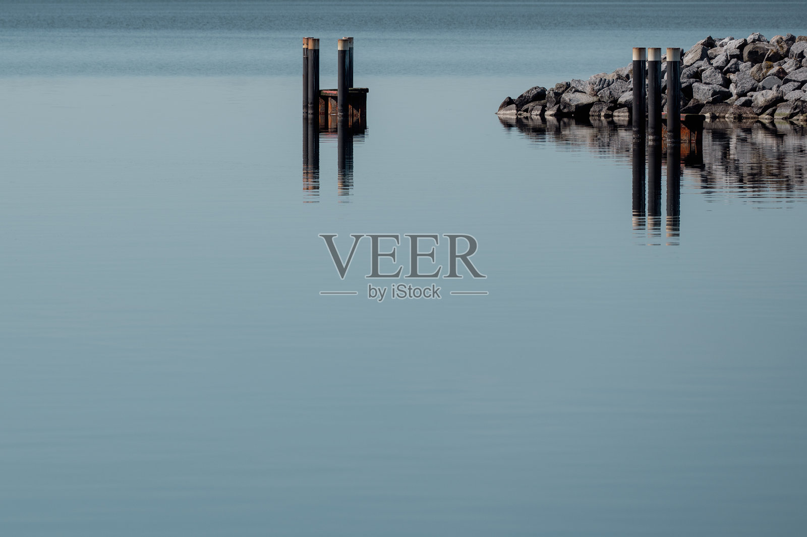 平静如镜的水面，港口入口的局部景象。照片摄影图片