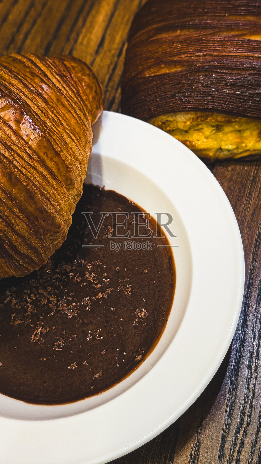 木桌上新鲜的金黄色羊角面包蘸着浓稠的热巧克力酱照片摄影图片