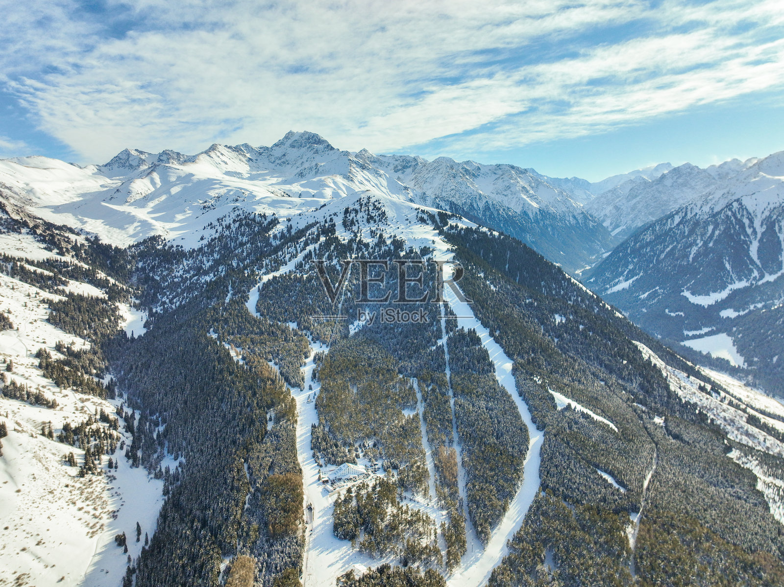 高耸的山峰间，滑雪道蜿蜒穿过山林照片摄影图片